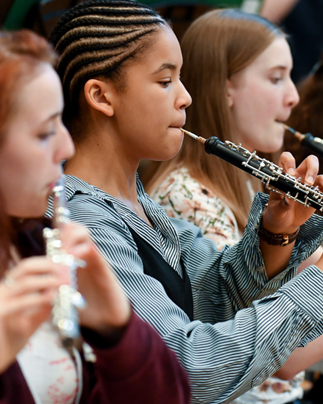 A group of young students, performing on woodwind instruments.